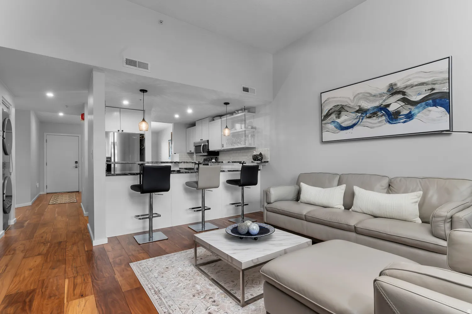 Open-concept living area featuring wood-finish flooring, recessed lighting, and a kitchen island with seating