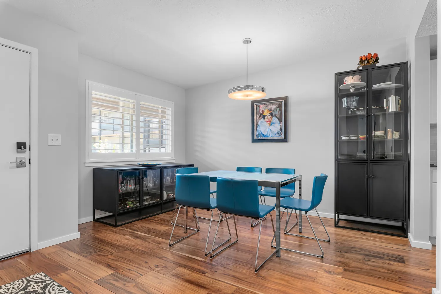 Dining area featuring wood-finish flooring, a contemporary pendant light fixture, and white plantation shutters