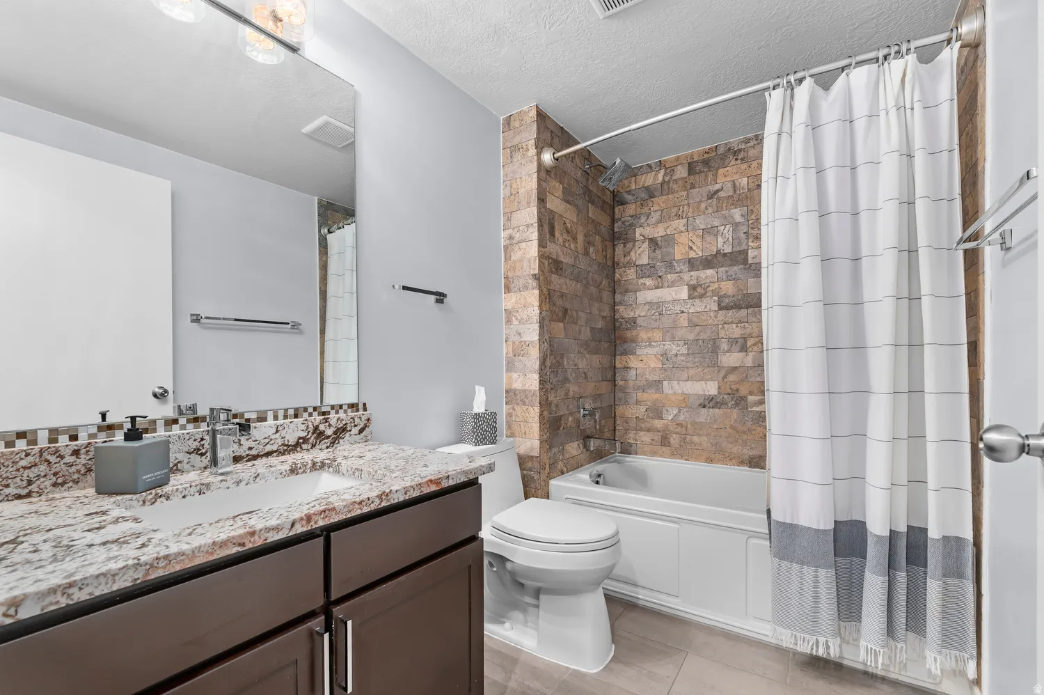 Modern bathroom featuring a vanity with a granite countertop, undermount sink, and dark wood-finish cabinetry