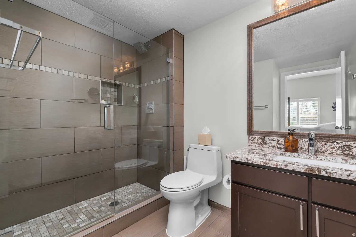 Shower featuring glass enclosure, tiled walls with an accent band, and a tiled floor