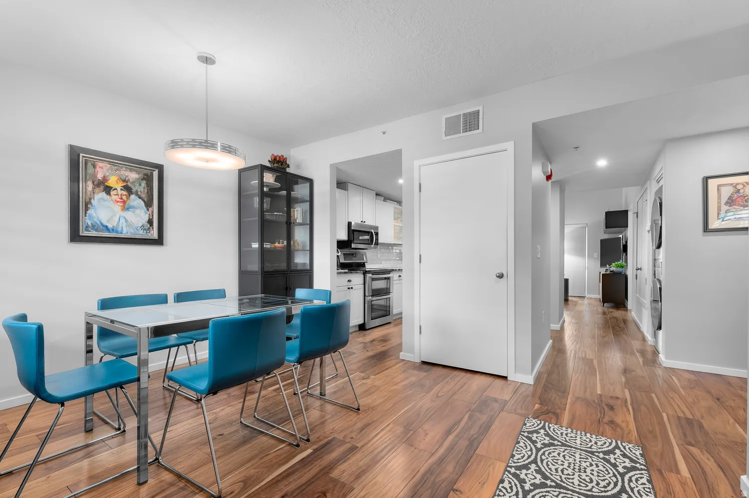 Dining area featuring wood-finish flooring, a contemporary overhead light fixture, and a built-in display cabinet