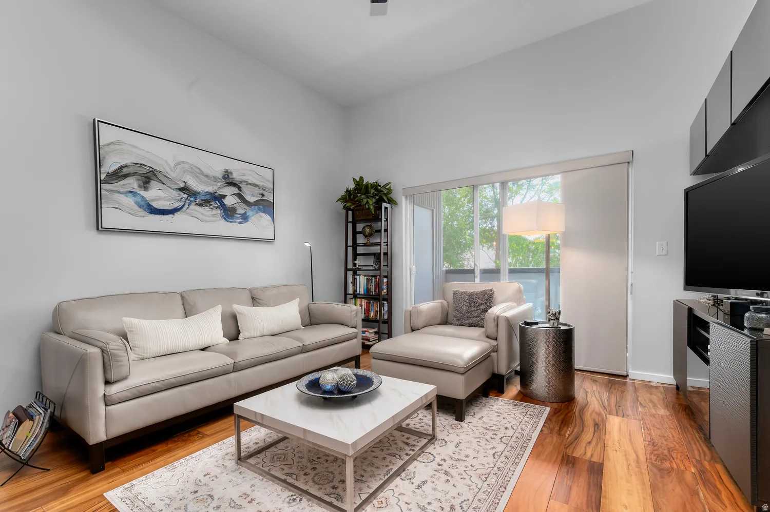 Living area featuring wood-finish flooring, a wall of glass doors opening to the exterior, and a high vaulted ceiling