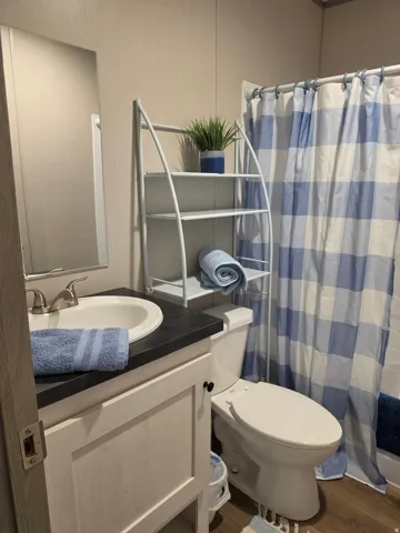 Bathroom 2, Well-appointed bathroom featuring a white vanity with a dark countertop, an integrated sink with a brushed nickel faucet, wood-finish flooring, and a white toilet