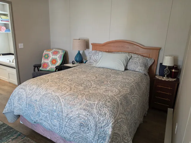 Primary Bedroom with wood-finish flooring and light-toned wall paneling