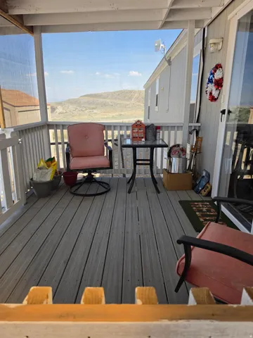 Screened porch featuring wood-finish decking, white railings, and a hillside backdrop