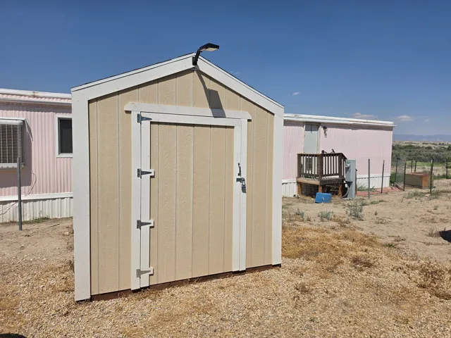 Freestanding second storage shed with beige siding and white trim