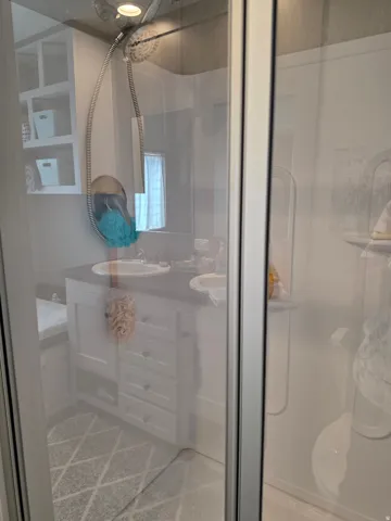 Shower enclosure with a handheld showerhead and a clear glass door