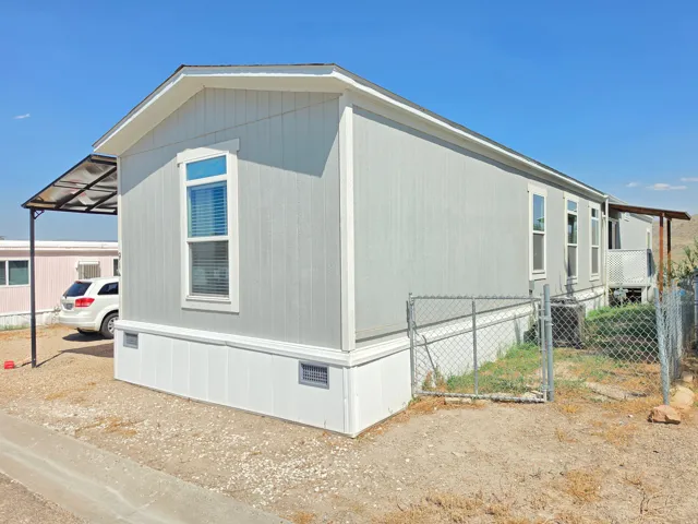 Light gray manufactured home with white trim and a covered carport