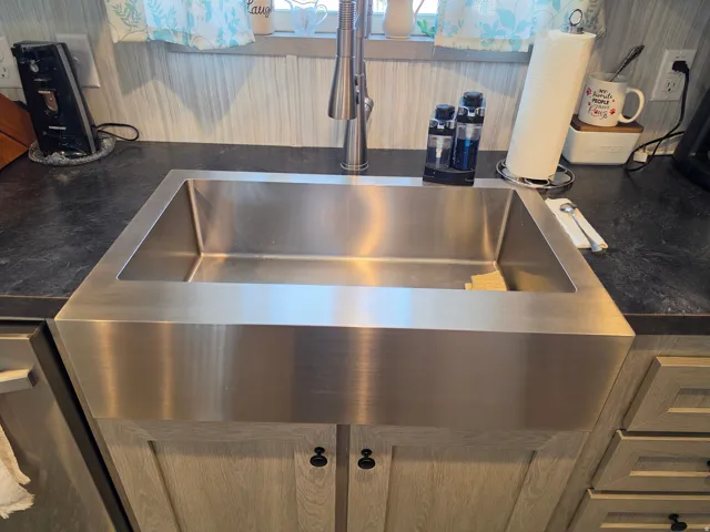 Stainless steel farmhouse sink featuring a brushed finish and a single basin