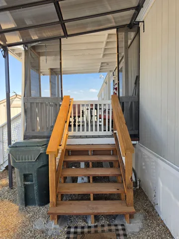 Exterior wood staircase with natural finish handrails leading to a screened porch