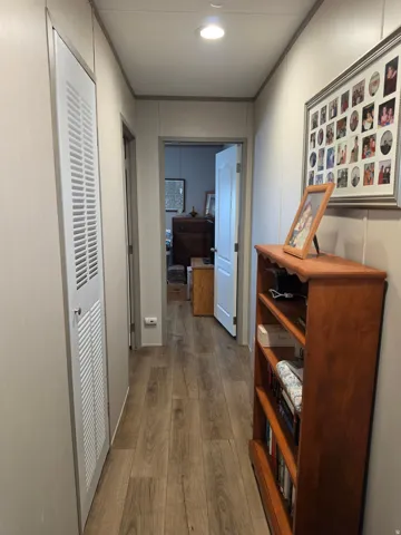 Hallway featuring wood-finish flooring, recessed lighting, and a white louvered door