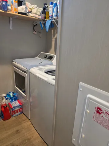 Dedicated utility area featuring wood-finish flooring, a built-in shelf, and a clothing rod
