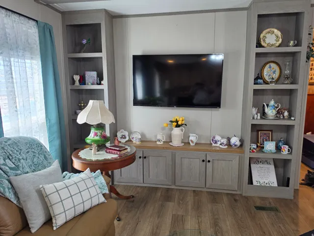 Built-in entertainment center featuring open shelving, base cabinetry with wood-finish countertops, and wood-finish flooring