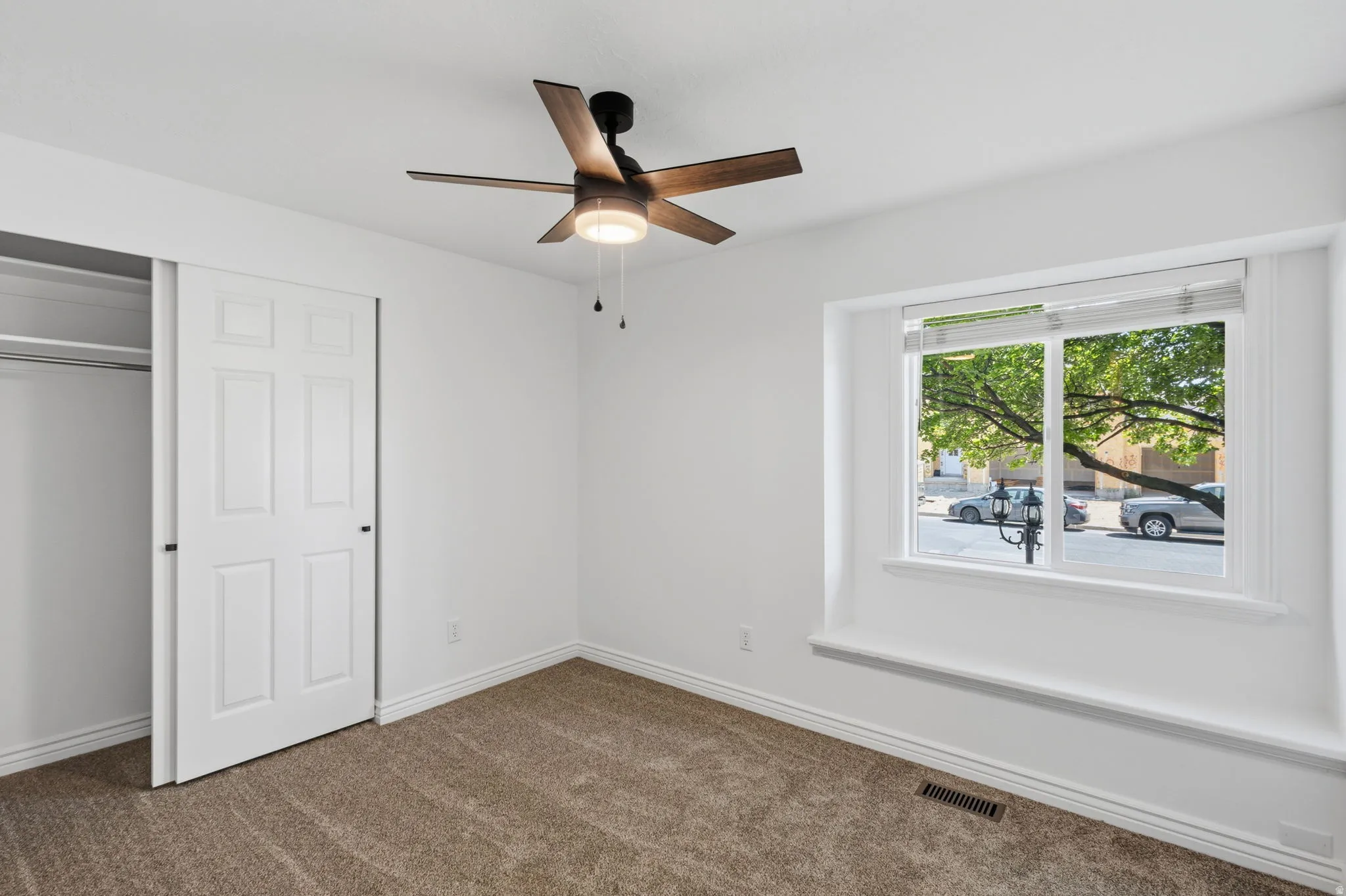 Bed with a new ceiling fan with integrated lighting, a double-paned window, and a built-in closet with bi-fold doors
