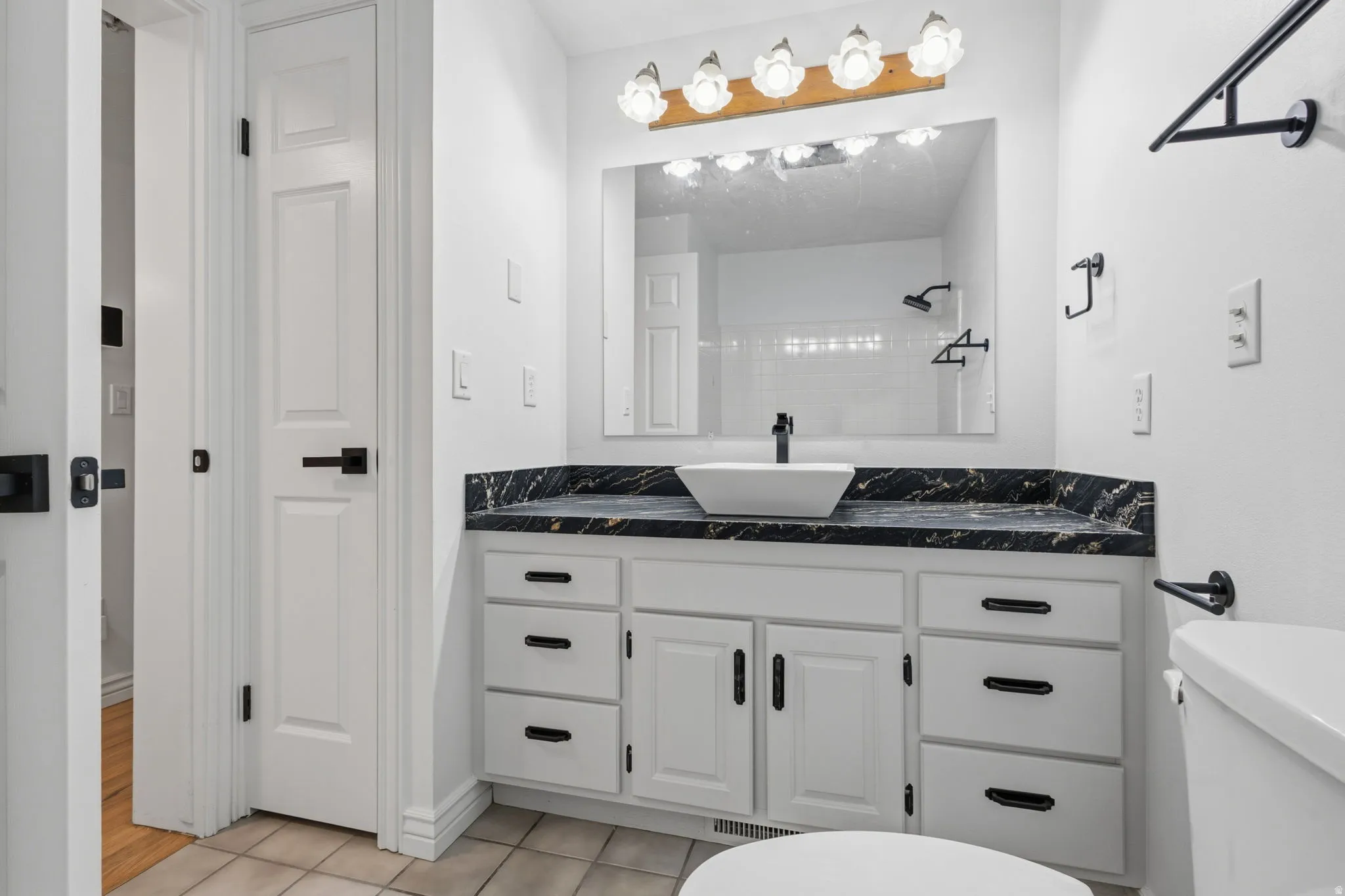 White vanity with new black hardware, granite countertop, and a vessel sink with new matte black faucet