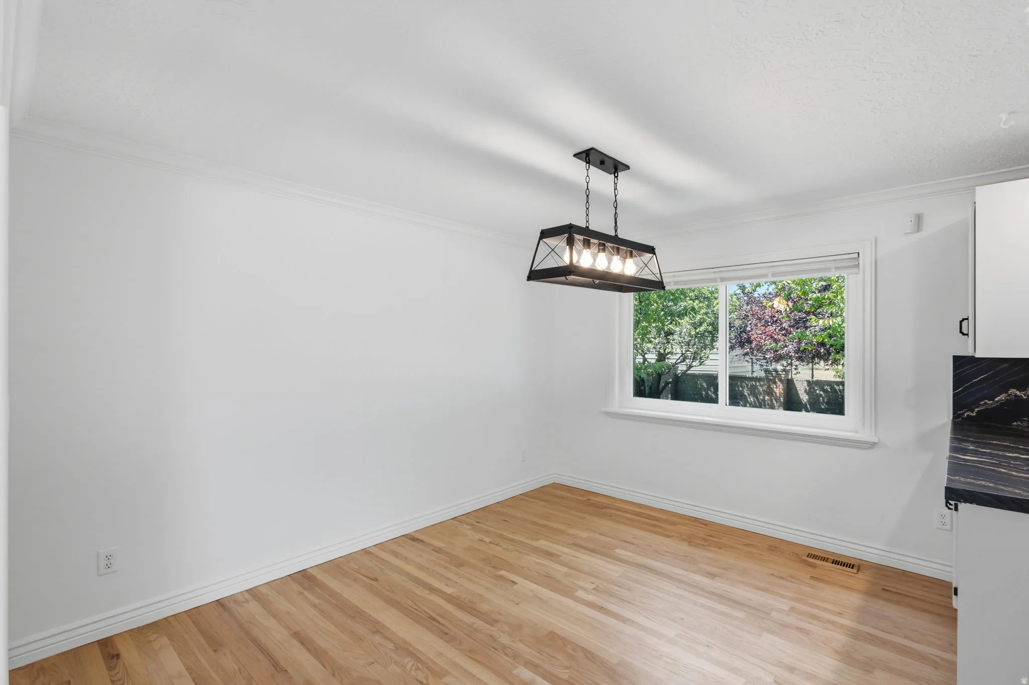 Dining area featuring hardwood flooring, a contemporary black metal chandelier, new paint and window