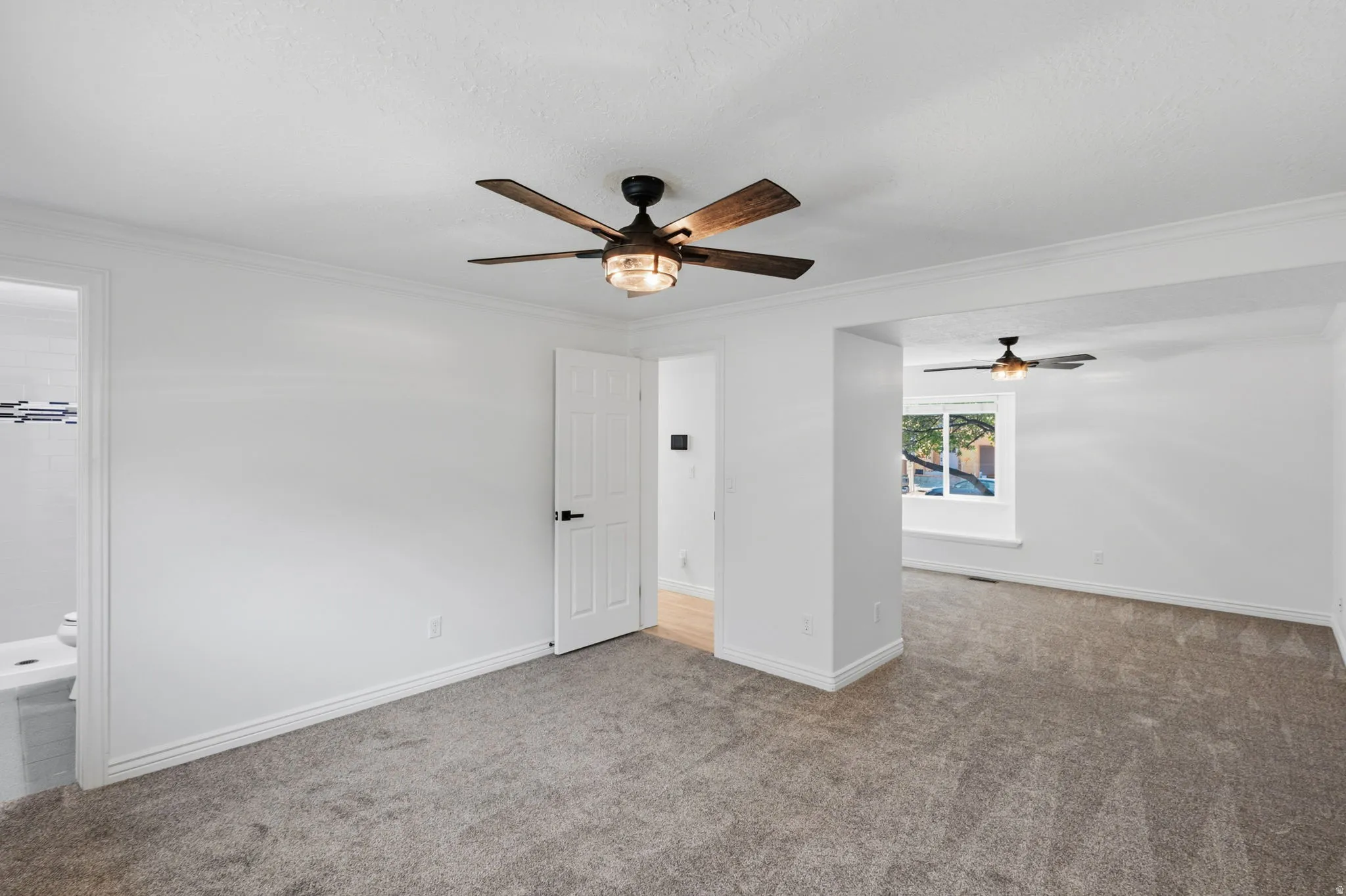 Spacious primary bedroom featuring new carpet, crown molding, and a new contemporary ceiling fan with integrated lighting