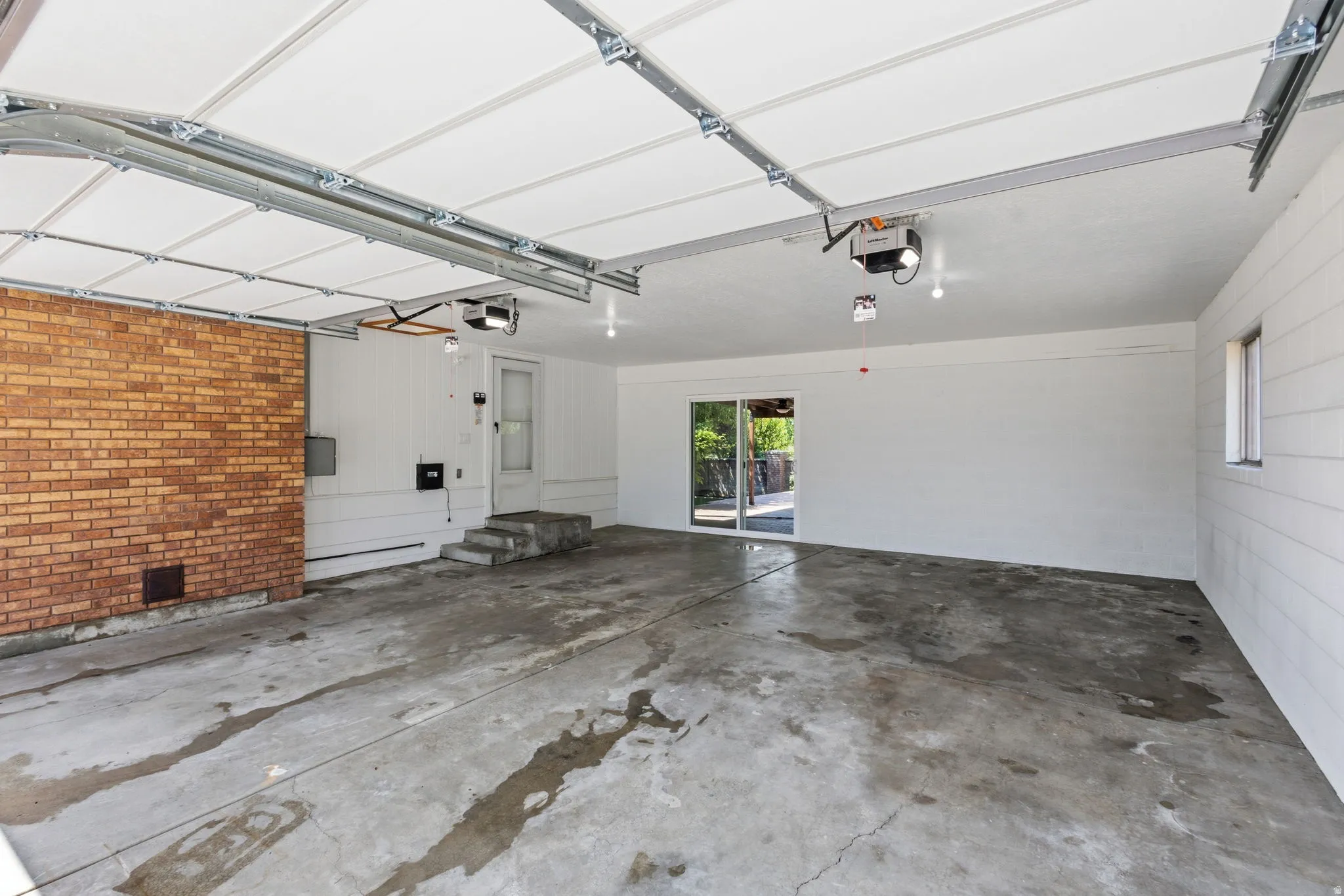 Spacious 2-car, extra-deep garage with concrete flooring and sliding doors leading to the backyard