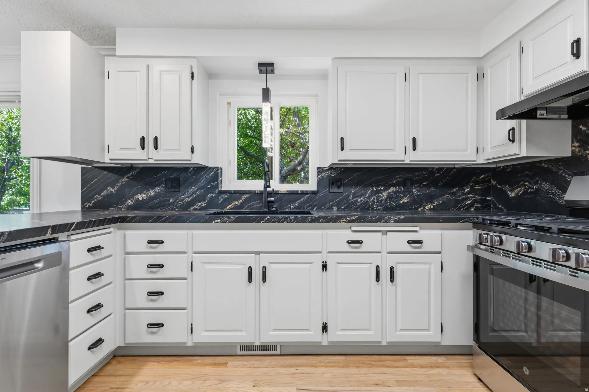 Fully updated kitchen featuring granite countertops and backsplash, refinished cabinets with new hardware, brand new stainless steel appliances, and hardwood flooring