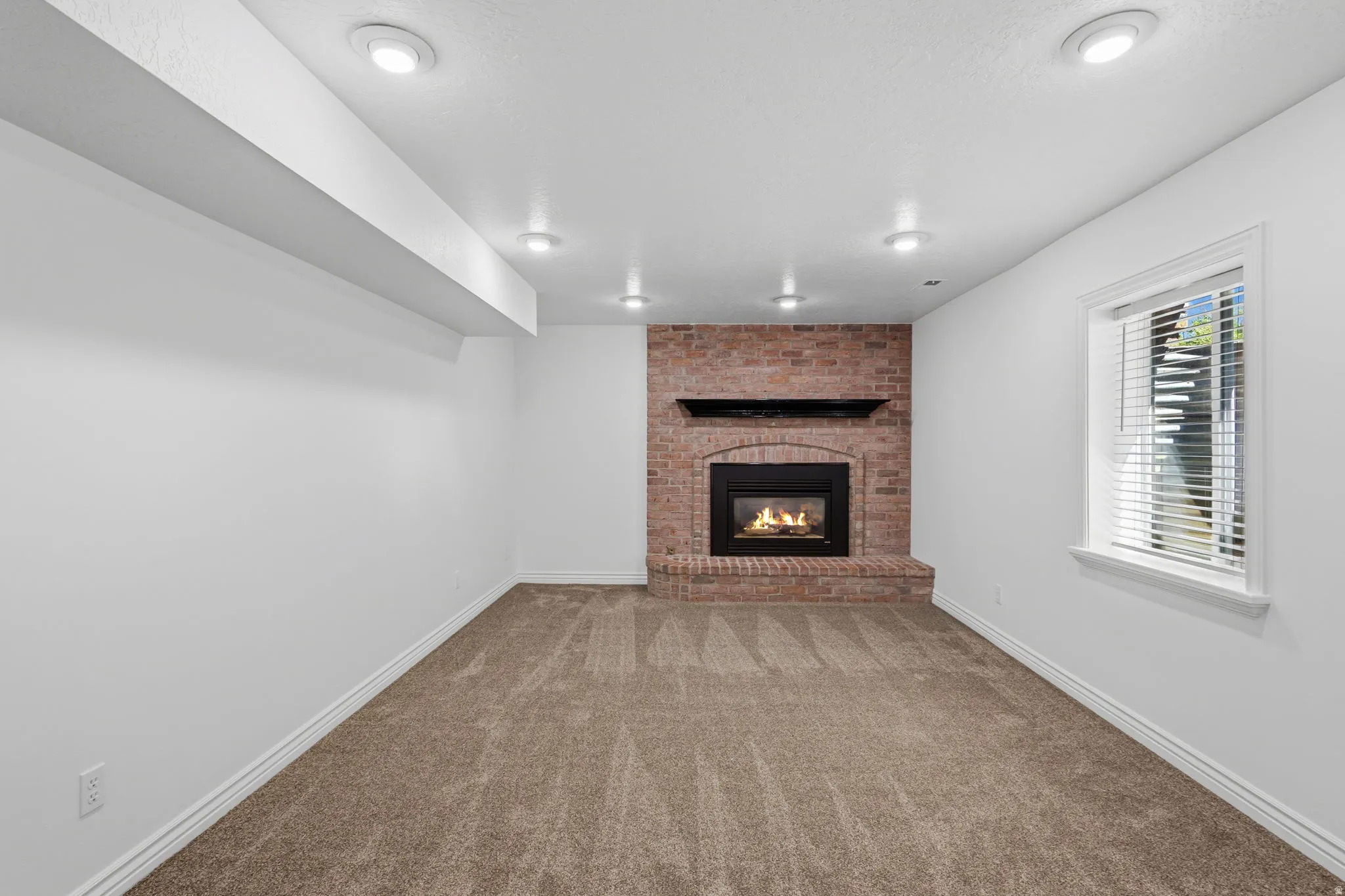 Spacious living room featuring gas fireplace, new carpeting, and new paint and lighting.