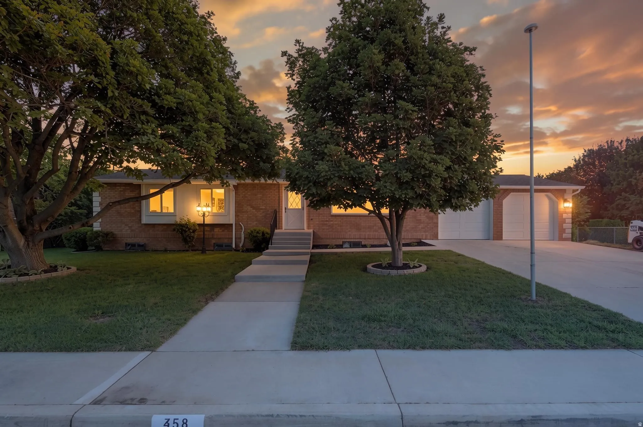 Brick exterior residence featuring a concrete walkway, established front lawn, and a multi-car driveway leading to a two-car extra-deep garage