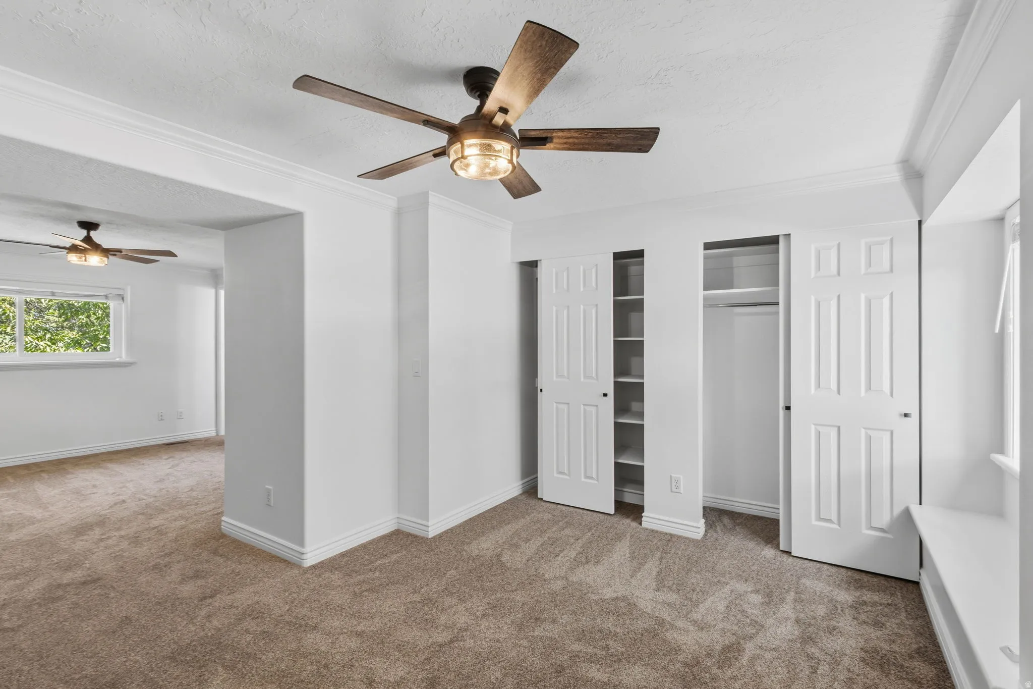 Spacious primary bedroom with large closet space, all new carpet, paint, ceiling fan, and lighting