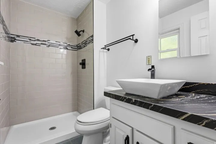 Primary bathroom featuring a walk-in shower with new tile and decorative accent band