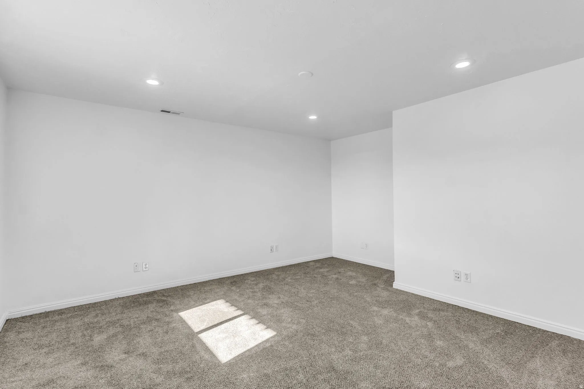 Recessed ceiling lighting, neutral carpeting, and white walls