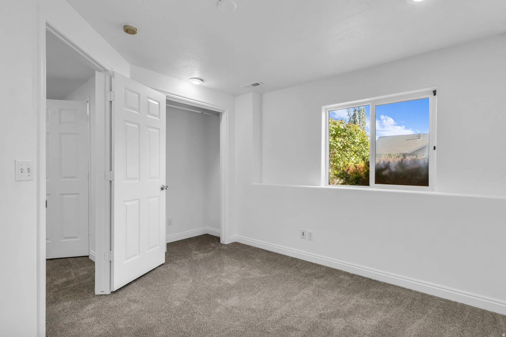 Wall-to-wall carpeting with white baseboards and a large window