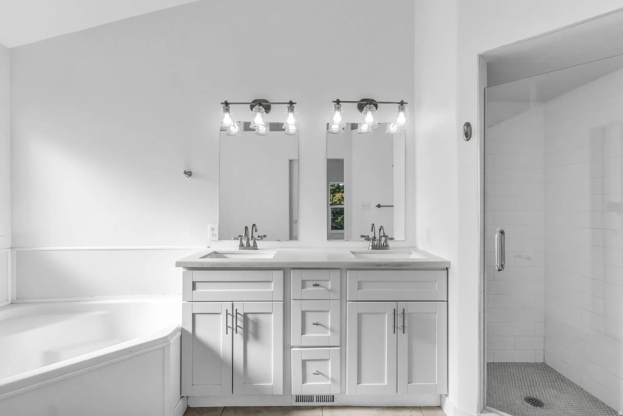 Primary en suite bathroom. Dual vanity with white cabinetry, light countertops, and brushed nickel hardware
