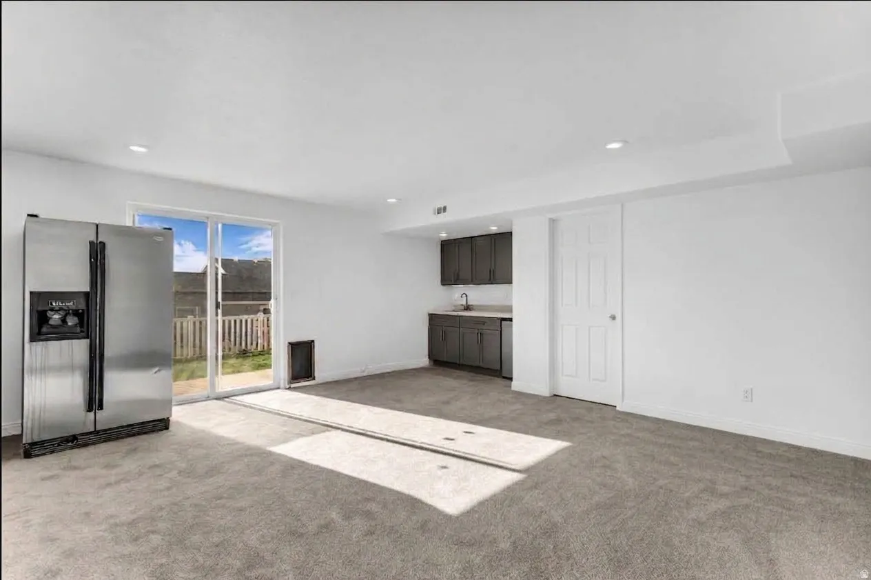 Recessed lighting, sliding glass door, new carpeting, built-in cabinetry, and a stainless steel refrigerator