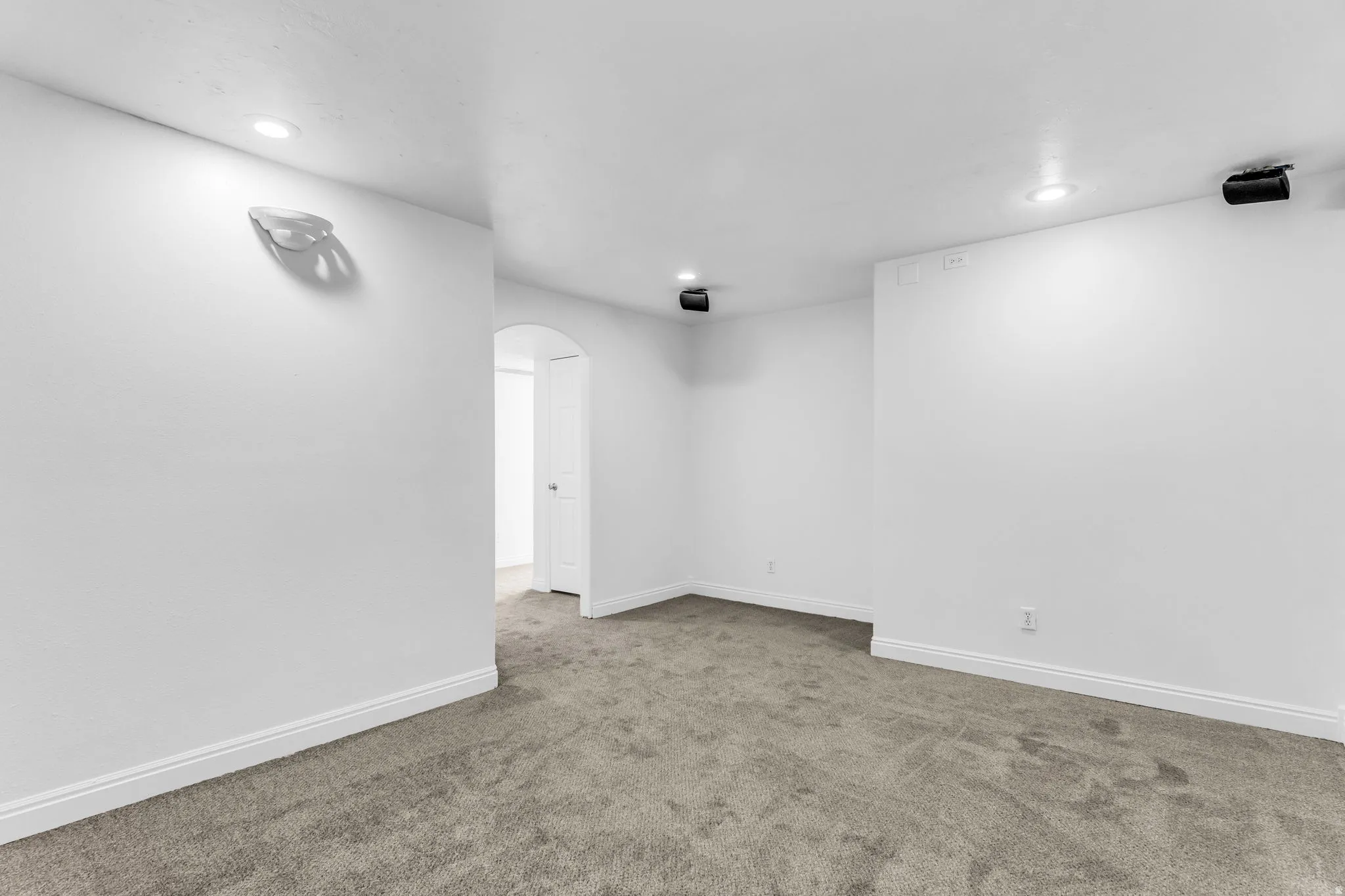 Recessed lighting, arched doorway, and soft new carpeting