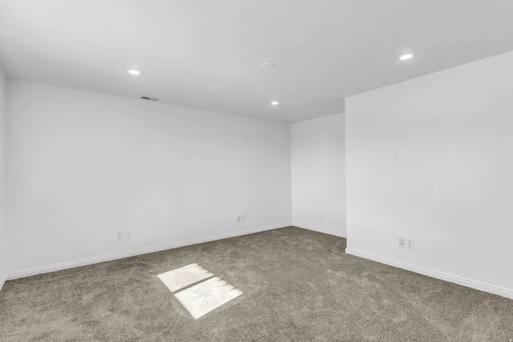 Recessed ceiling lighting, neutral carpeting, and white walls