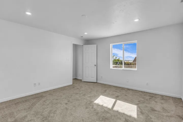Recessed lighting, carpeted flooring, white trim, white paneled door, and a single window