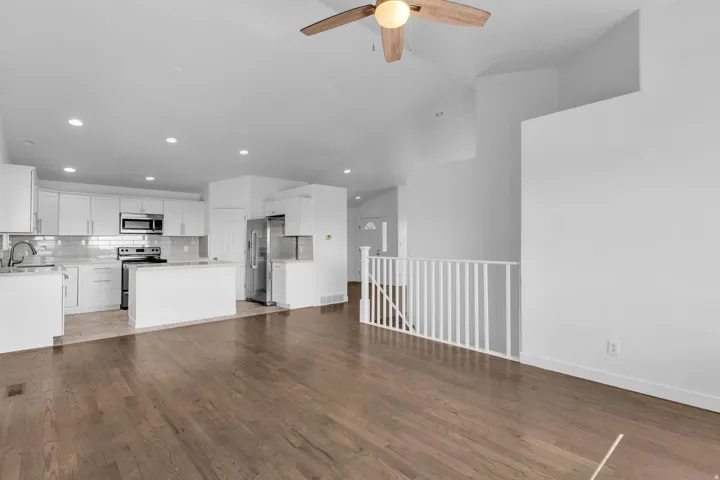 Open-concept living space with wood-finish flooring, vaulted ceilings, and a ceiling fan