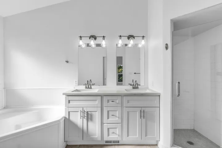 Primary en suite bathroom. Dual vanity with white cabinetry, light countertops, and brushed nickel hardware
