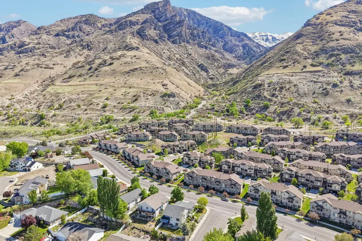 Aerial view of a residential community nestled in a mountain valley, showcasing multiple townhome-style units with individual driveways and landscaping