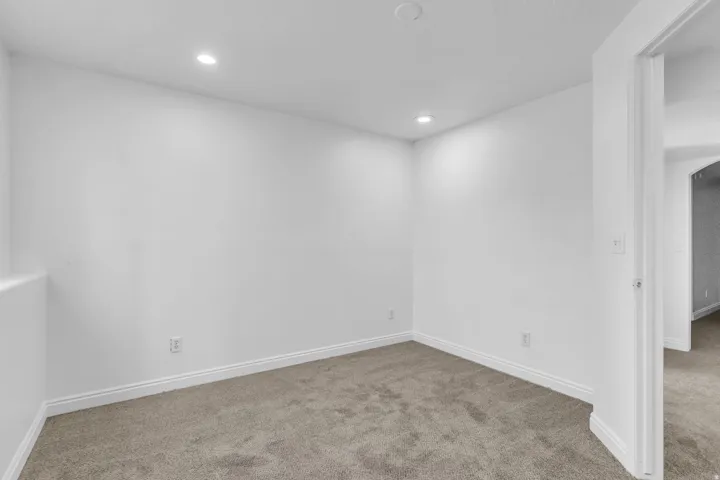 Neutral wall finish, recessed ceiling lighting, light-colored carpet, and white trim