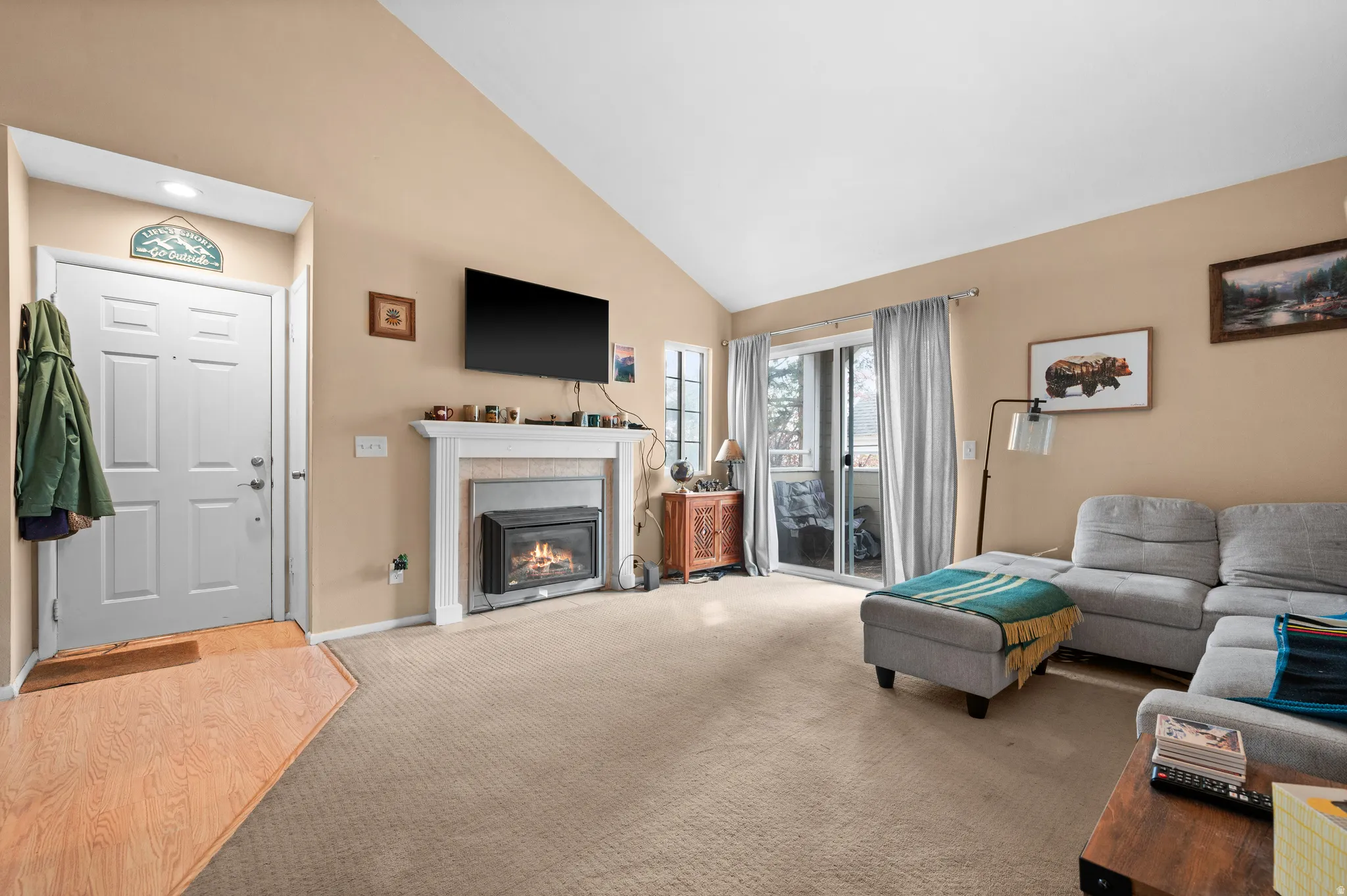 Living area featuring vaulted ceilings, a built-in fireplace with a white mantel, and a sliding glass door