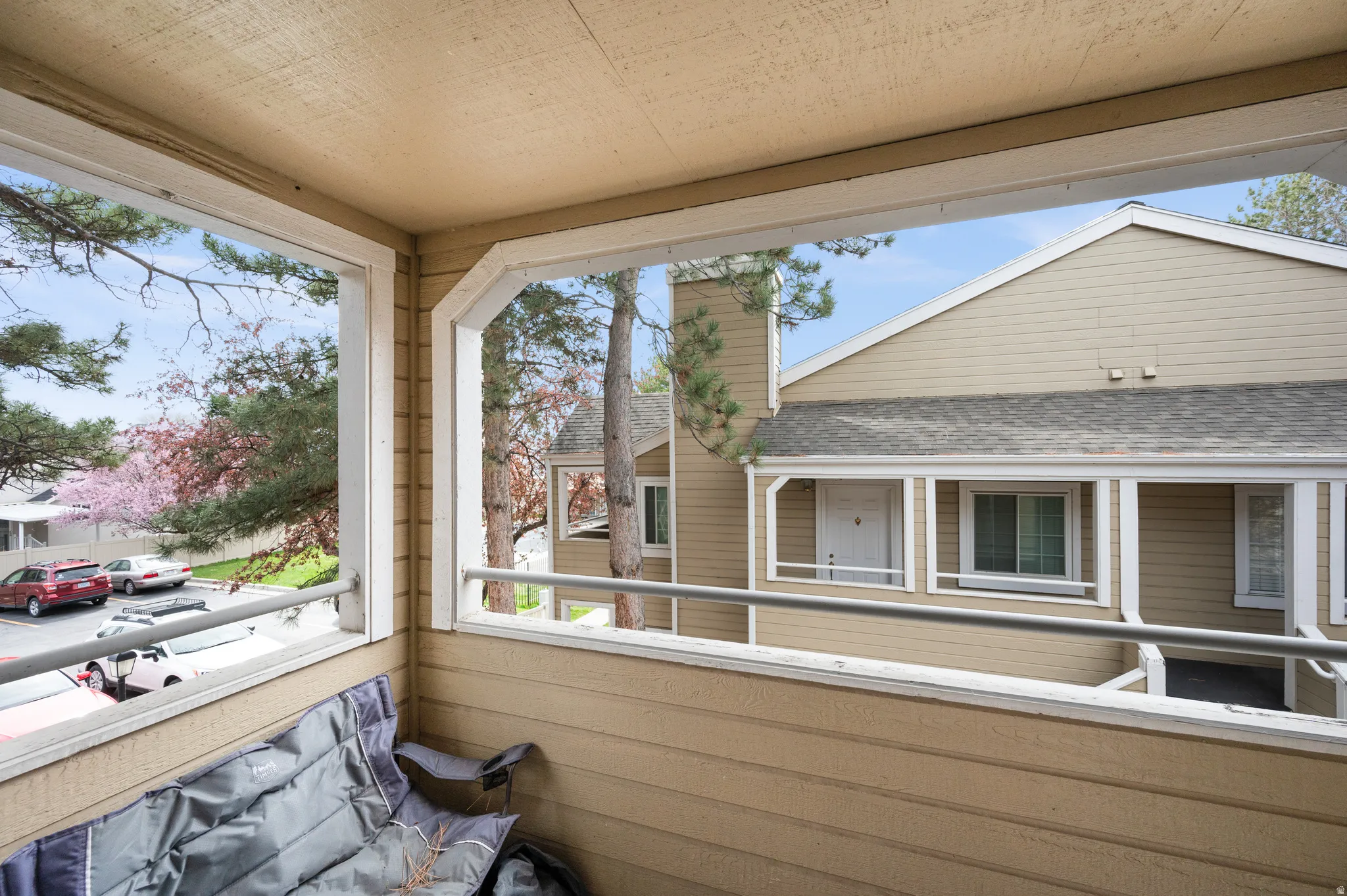 Covered balcony featuring tan siding, a flat ceiling, and metal railings