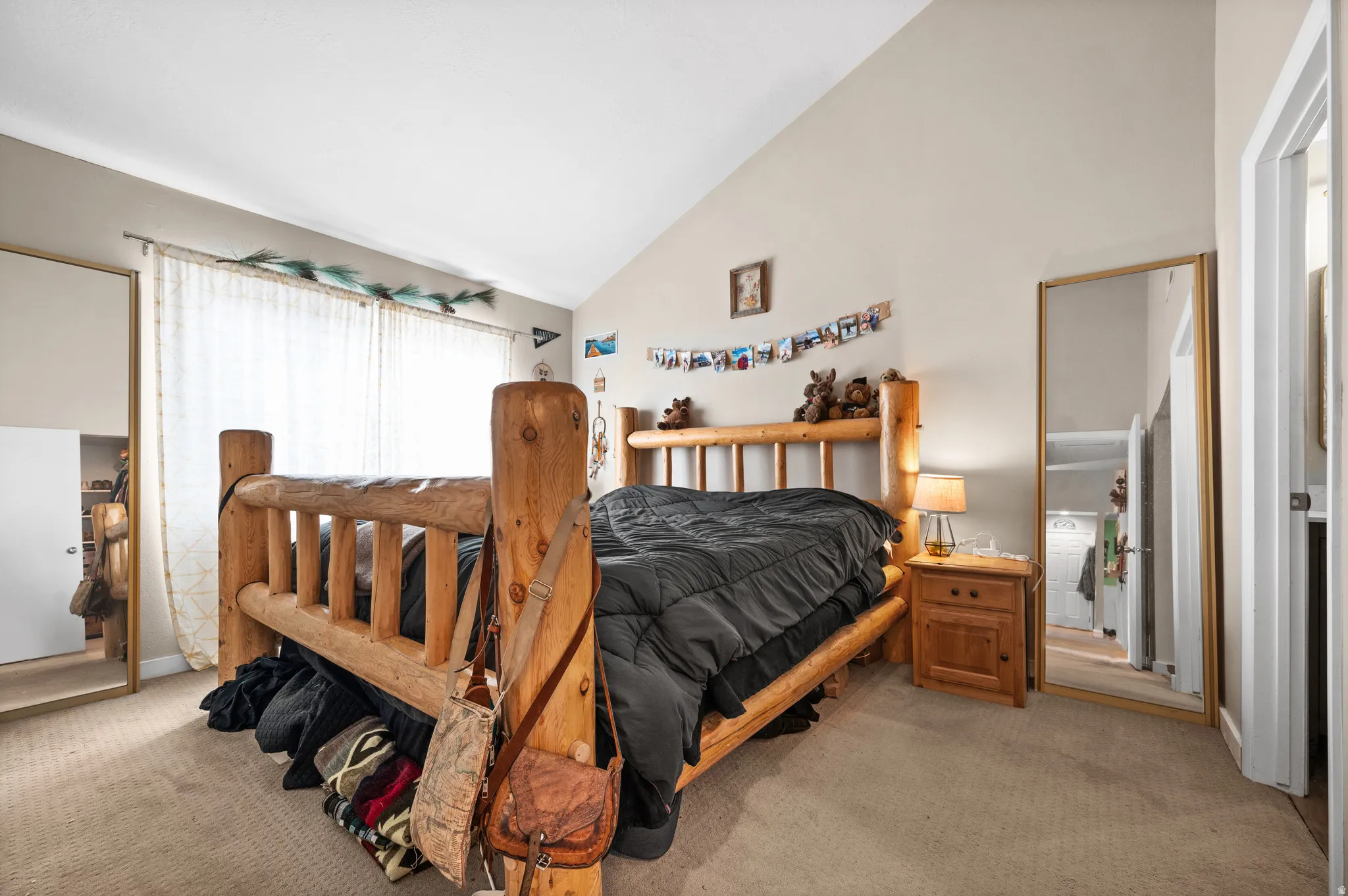 Carpeted room featuring a vaulted ceiling and window with sheer curtains