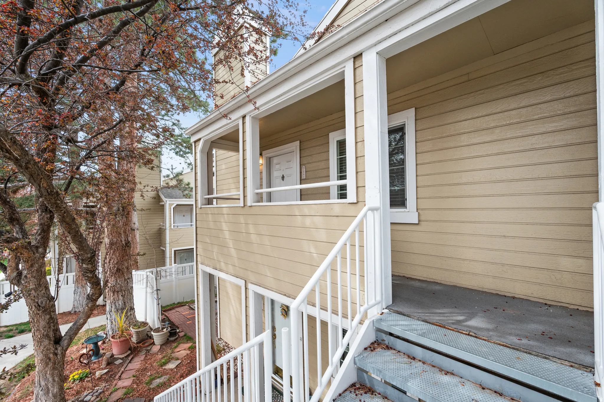 Upper-level entry with white railing and neutral-toned siding