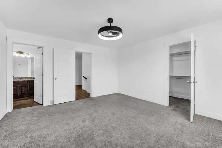 Spacious bedroom featuring plush carpeting throughout, abundant natural light from multiple windows, and generous closet storage