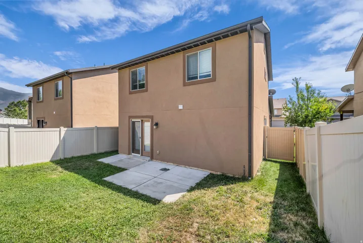 Private backyard space with a concrete patio, perimeter fencing, and a side access gate