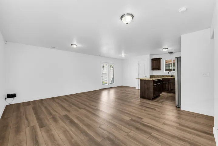 Open-concept living area featuring wood-finish flooring, recessed lighting, and a white color palette