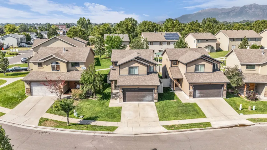Desirable suburban neighborhood featuring multiple two-story residences with tan and earth-tone exteriors, two-car garages, manicured lawns, and mature landscaping