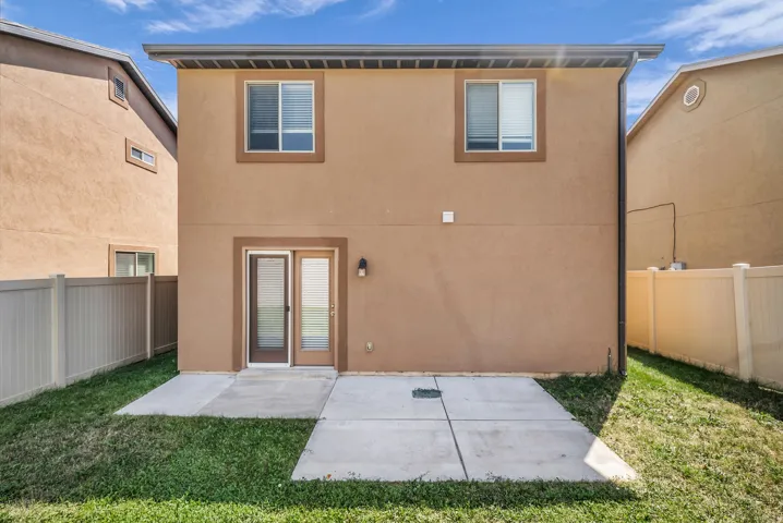 Rear exterior featuring a stucco finish, dual-pane windows, and a ground-level patio