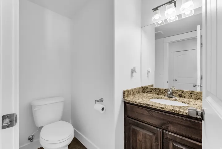 Bathroom vanity featuring a granite countertop, undermount sink, dark wood-finish cabinetry, and a chrome faucet