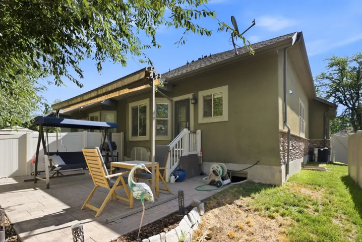 Rear exterior featuring a stone and stucco finish, a paved patio, and a staircase with white railings