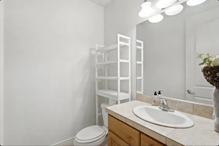 Clean and functional bathroom featuring a wood-finish vanity with an oval porcelain sink, quartz countertop, and chrome faucet